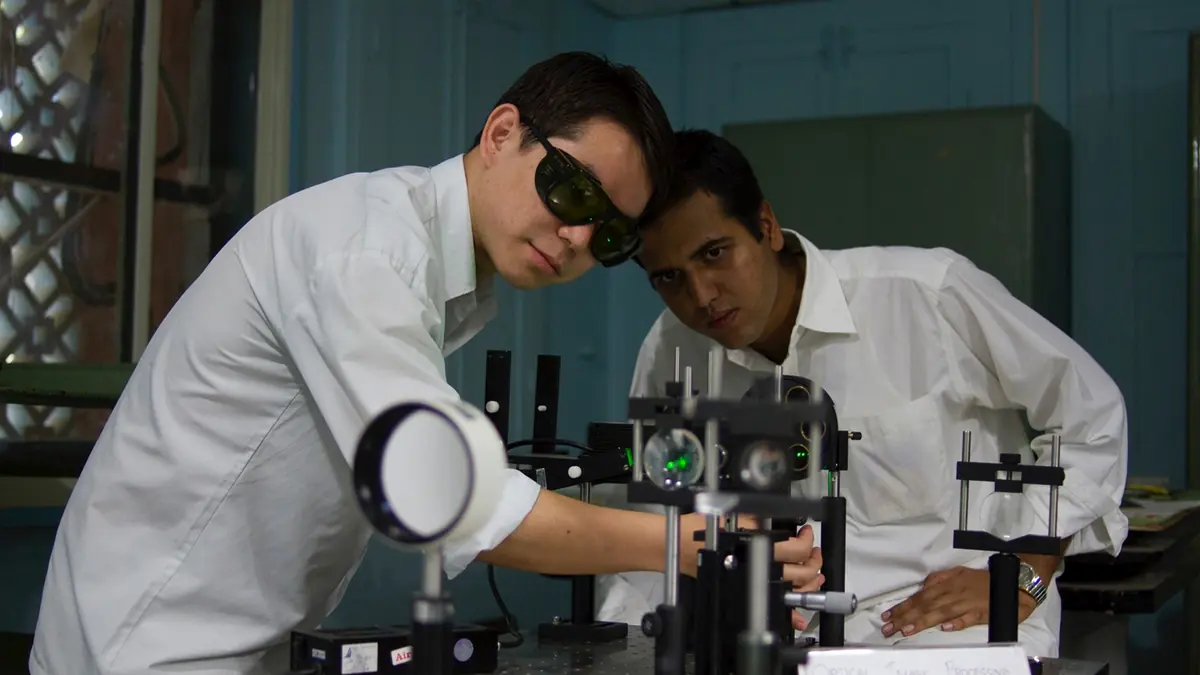 Researchers working with optical instruments in an SSSIHL laboratory